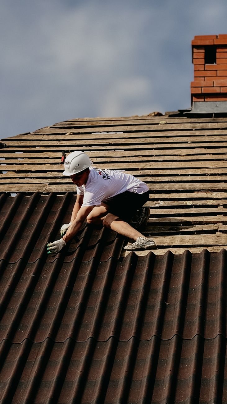 Pracovník kladie krytinu na streche rodinného domu