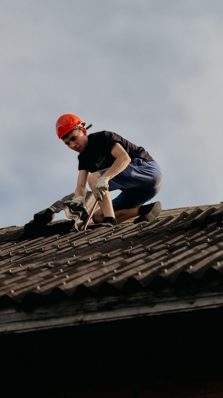 Pracovník vymieňa poškodenú škridlu na streche